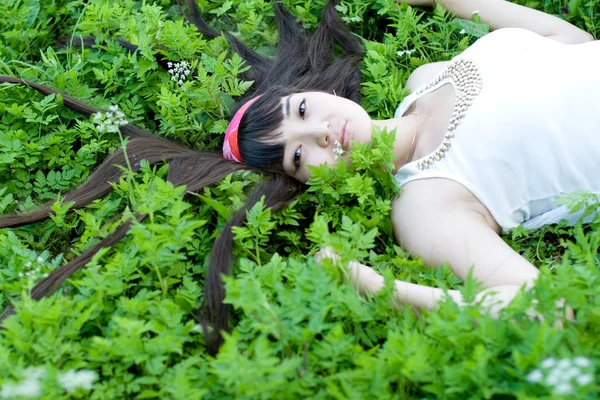 Closeup portret van een mooi meisje liggen onder bloemen — Stockfoto