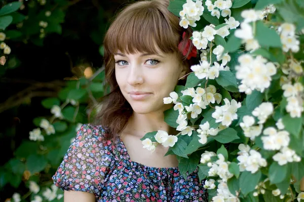 Closeup portrait of a beautiful girl standing among flowers — Stock Photo, Image