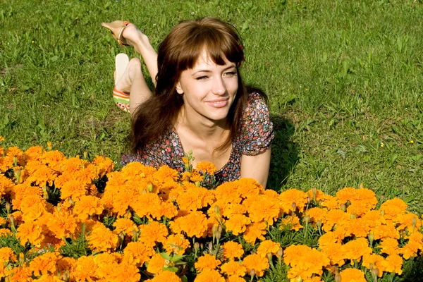 Vacker flicka ligger på äng med blommor — Stockfoto