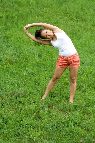 Flicka göra övningar i park — Stockfoto