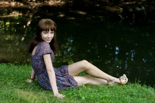 川の銀行に座っている美しい女の子 — ストック写真