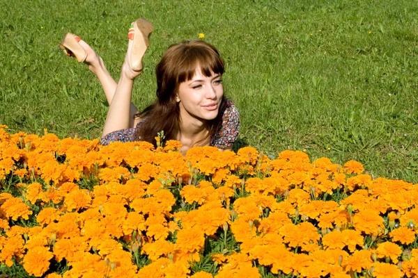 Menina bonita deitada no prado com flores — Fotografia de Stock