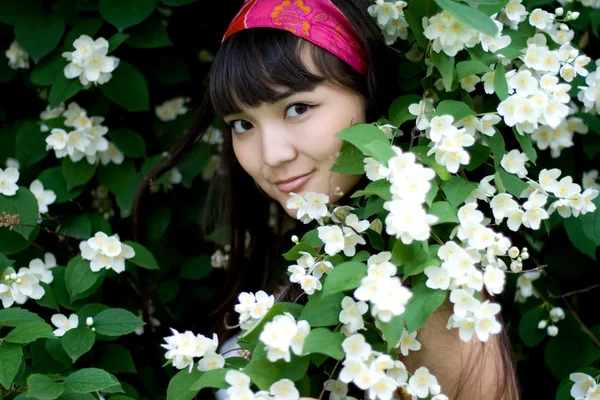 Closeup portrait of a beautiful girl standing among flowers — Stock Photo, Image