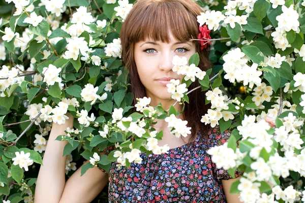 Retrato de cerca de una hermosa niña de pie entre flores — Foto de Stock