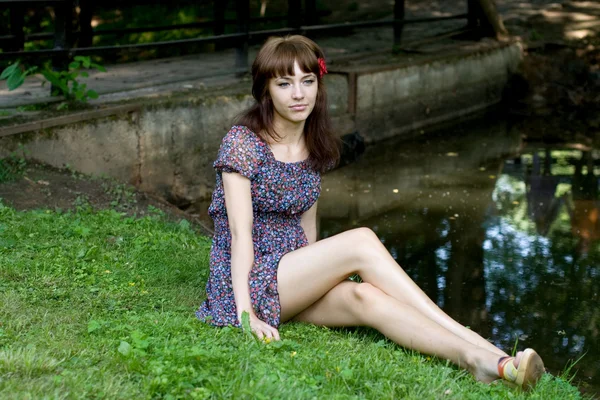 Hermosa chica sentada en la orilla de un río — Foto de Stock