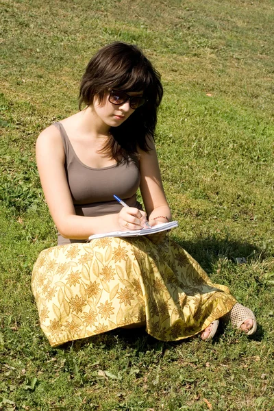 Meisje, zittend op het gras in park — Stockfoto