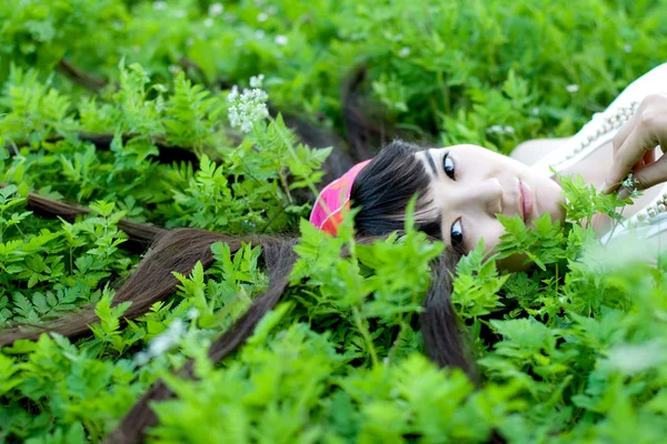 Closeup portrait of a beautiful girl lying among flowers — Stock Photo, Image