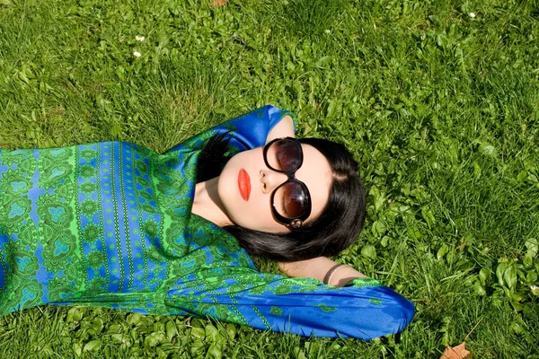 Flicka liggande på gräs i parken — Stockfoto