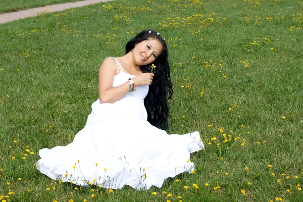 Красивая беременная девушка сидит на траве — стоковое фото