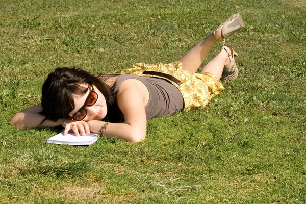 Dívka ležící na trávě v parku — Stock fotografie