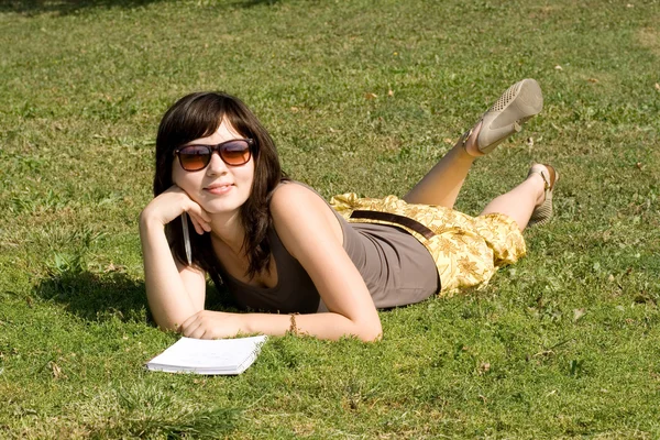 Kız parkta çimlerde yatıyor. — Stok fotoğraf