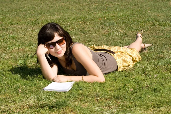 Kız parkta çimlerde yatıyor. — Stok fotoğraf