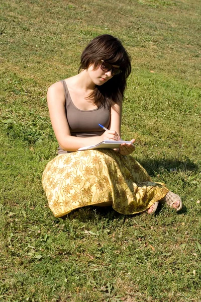 Девушка сидит на траве в парке — стоковое фото
