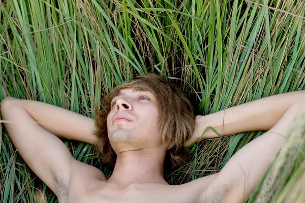 Hombre guapo acostado en la hierba — Foto de Stock