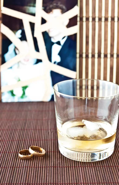 Glass of alcohol and wedding rings — Zdjęcie stockowe