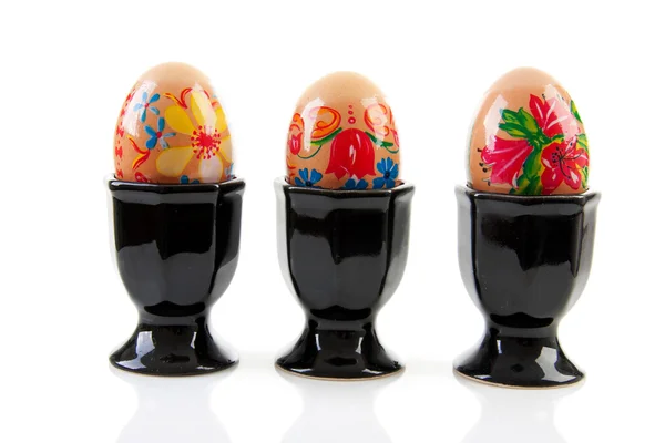 Three chicken eggs decorated by children in black holder — Stock Photo, Image