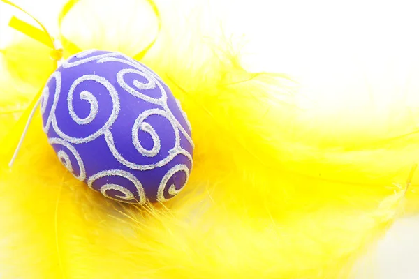 Œuf de Pâques violet sur plumes jaunes — Photo