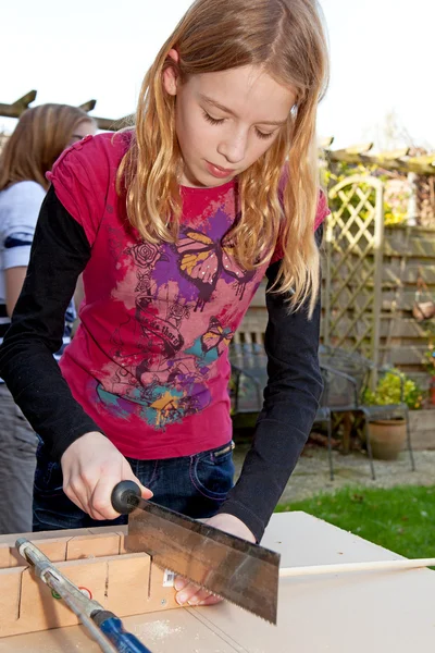 Girl is sawing a wooden stick — Stock Photo, Image
