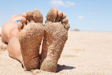 Bottom of male feet covered with sand clipart