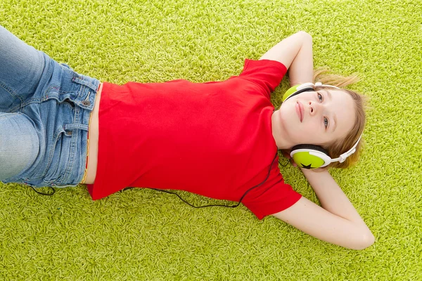 Flickan lyssna på musik med hörlurar på — Stockfoto