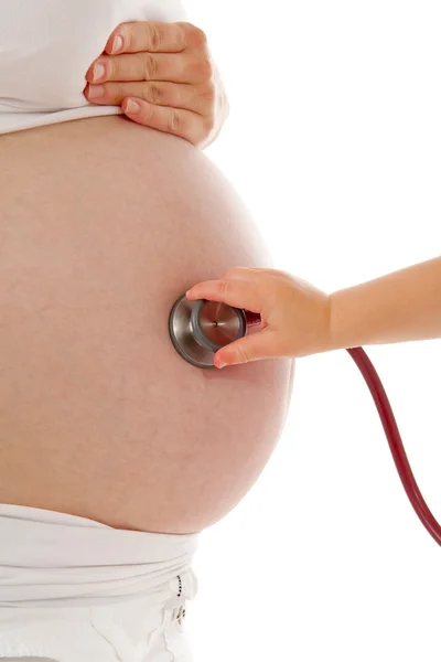 Детская рука со стетоскопом на беременном животе — стоковое фото