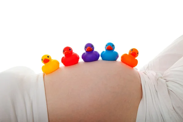 Pregnant belly with colorful rubber ducks — Stock Photo, Image