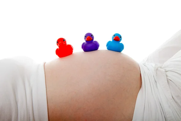 Беременный живот с разноцветными резиновыми утками — стоковое фото