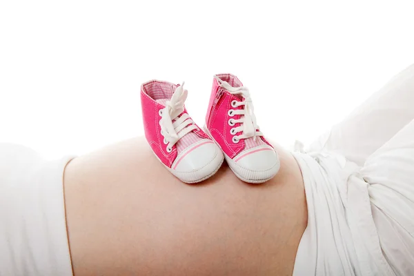 Barriga grávida com pequenos sapatos rosa — Fotografia de Stock
