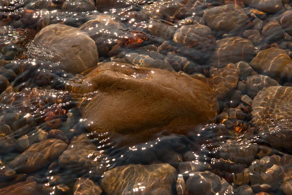 Guijarros con piedras están en el agua de mar clara Imagen De Stock
