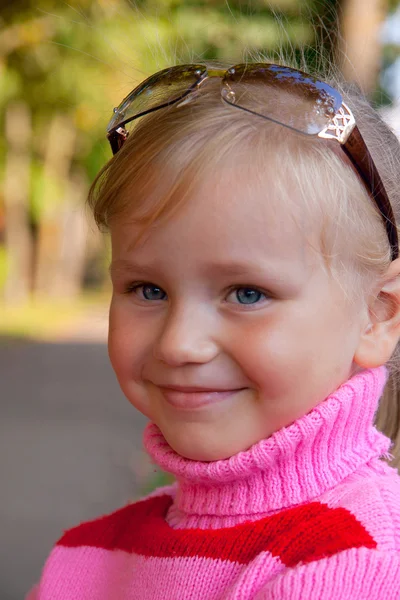 Kis szőke lány mosolyogva portré közelről a rózsa pulóver Stock Kép
