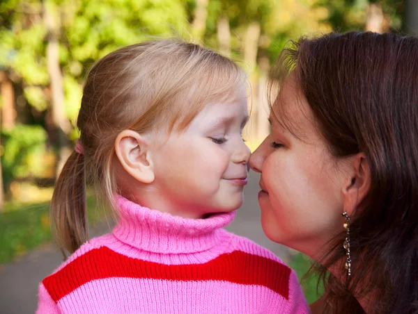 Little blond girl smiling portrait with her mother in a profile Stock Picture