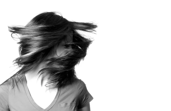 En ung kvinna som skakar hennes huvud med hennes hår som flyger omkring henne. — Stockfoto