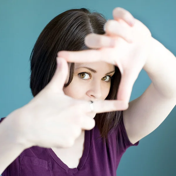 Kadının yüzü etrafında parmak çerçeve yapma — Stok fotoğraf