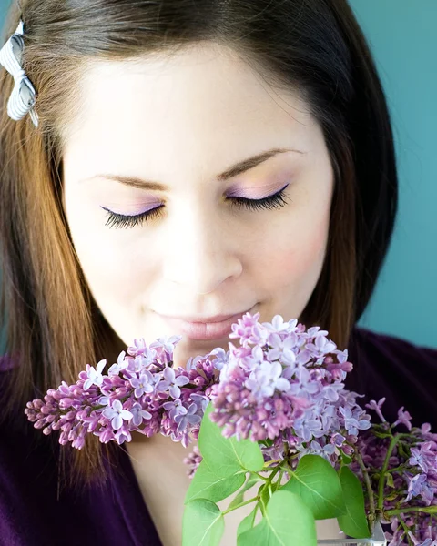 Jovem mulher cheirando lilases — Fotografia de Stock