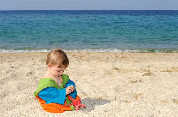 Meisje van de baby spelen met rode zeesterren op het strand — Stockfoto