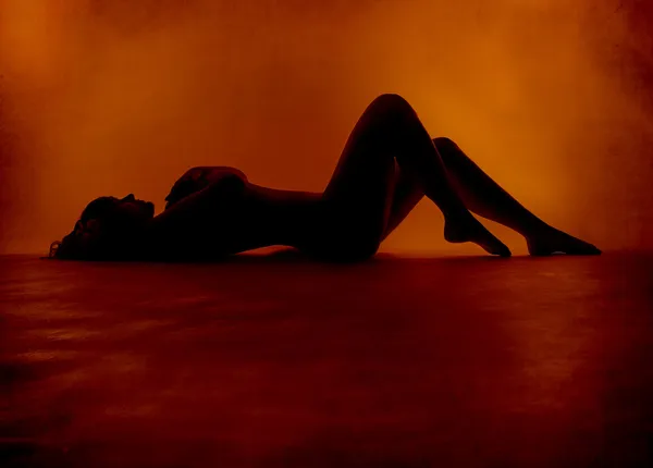 Naken sexig kvinna silhuett liggande på orange bakgrund — Stockfoto