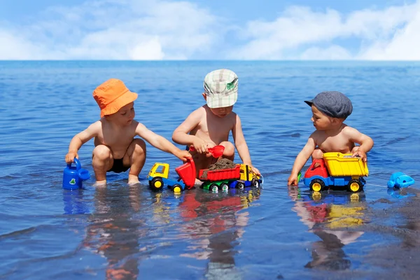 Üç erkek su sahilde oynarken — Stok fotoğraf