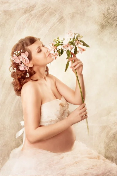 Mujer embarazada olfateando flores y soñando . — Foto de Stock