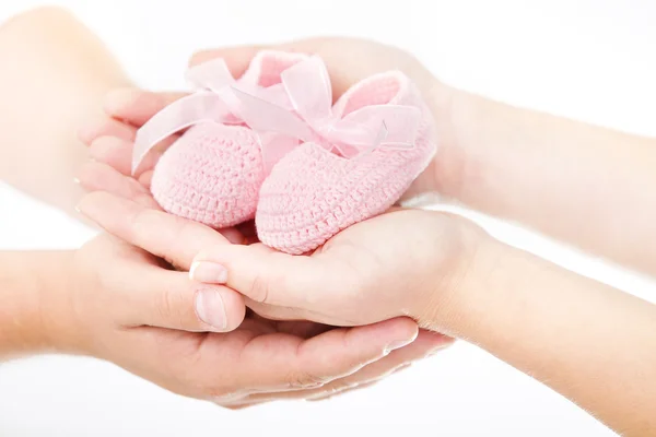 Mãos de mãe e pai segurando botas de bebê recém-nascido rosa. O — Fotografia de Stock