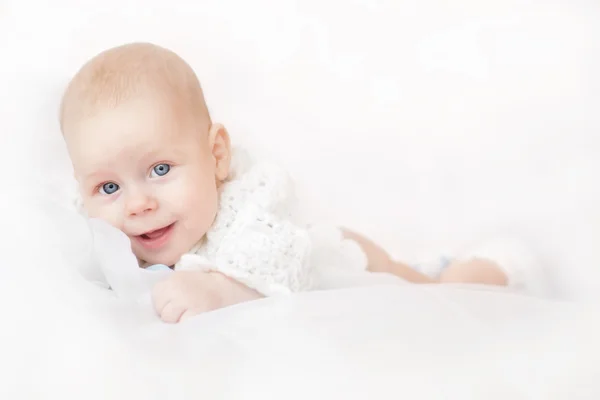Lächelnd entzückendes Baby auf weißem Hintergrund liegend — Stockfoto
