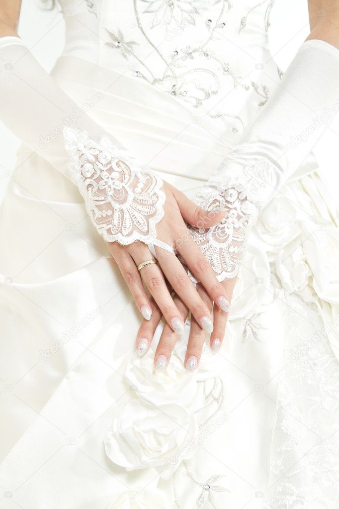 Bride's hands with manicure in white lace gloves