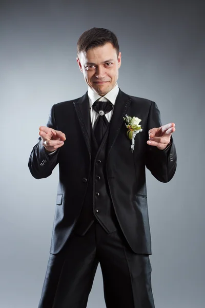 Handsome man in black suit pointing fingers in front of himself. — Stock Photo, Image