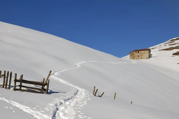 Casa de montaña en un paisaje nevado —  Fotos de Stock