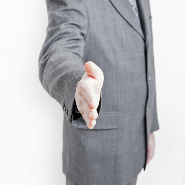 A business man makes a hand shake gesture in your direction.