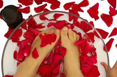Feet of child in spa with rose petals and stone clipart