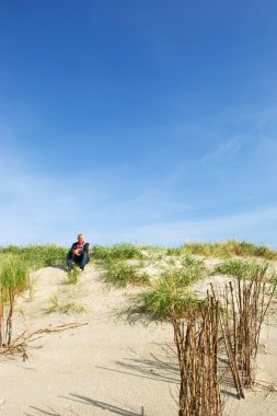 adam dunes içinde oturuyor