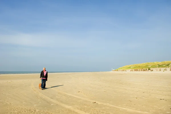 Літній чоловік зі своїм собакою на пляжі — стокове фото