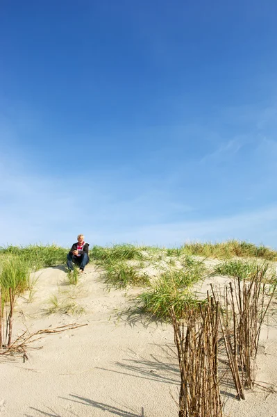 Man is sitting in the dunes — Stock Photo, Image