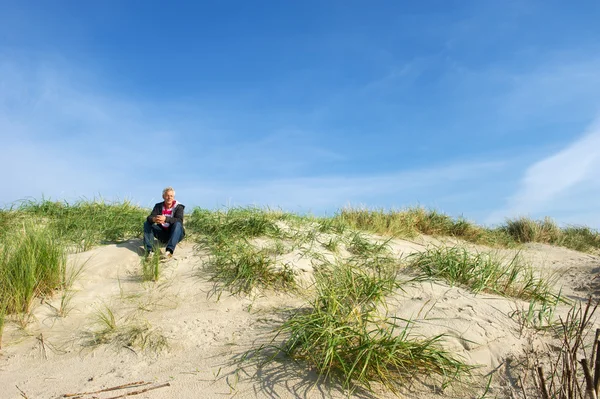 Man is sitting in the dunes — Stock Photo, Image