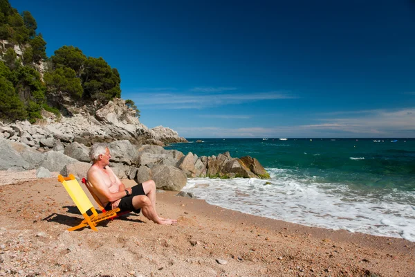 Yaşlı bir adam sahilde — Stok fotoğraf